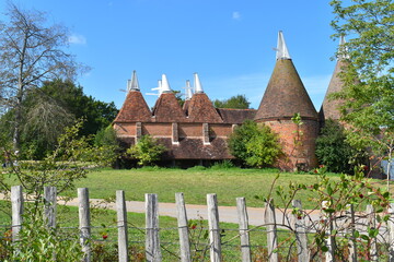 Traditional oast house building found in Kent and Sussex counties. It is a freestanding kiln with a plenum chamber fired by charcoal at ground level and above drying floor for hops used in beer making - obrazy, fototapety, plakaty