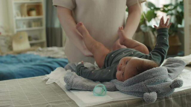 Close up of unrecognizable Caucasian woman changing diaper on her sweet mixed-race baby girl