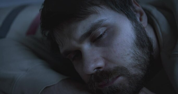 Exhausted, pensive man in depression lies on the bed. Unkempt. 