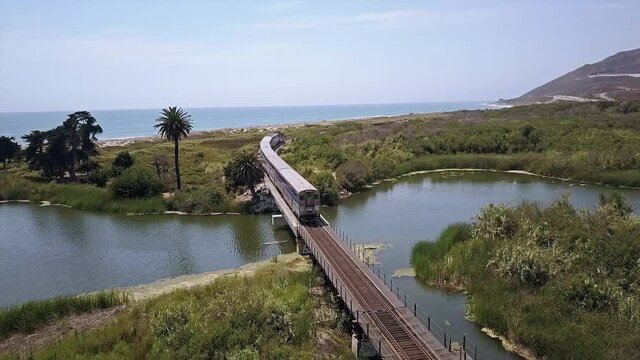 Aerial view of passenger train crossing train trestle near ocean
