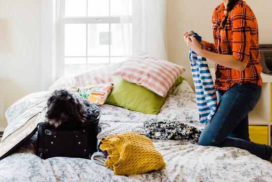 teen packing her suitcase with her dog