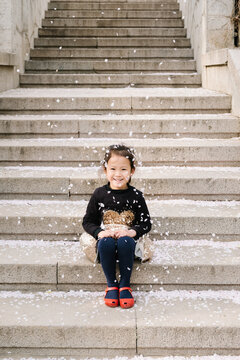 Adorable girl playing with cherry blossom petals