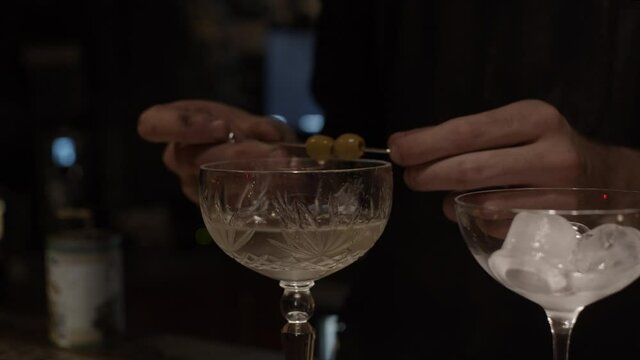 Decorating cocktail with olives , shallow depth of field