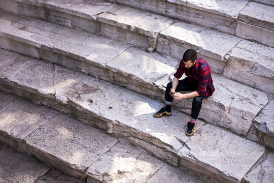 Young man in a shirt sitting at Plovdiv's amphitheater