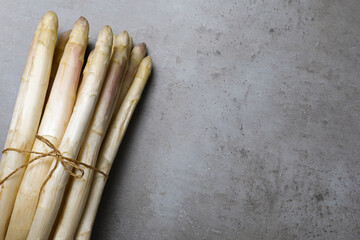 Bunch of fresh white asparagus on grey table, top view. Space for text