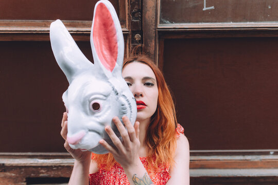 ginger woman hiding behind a bunny mask