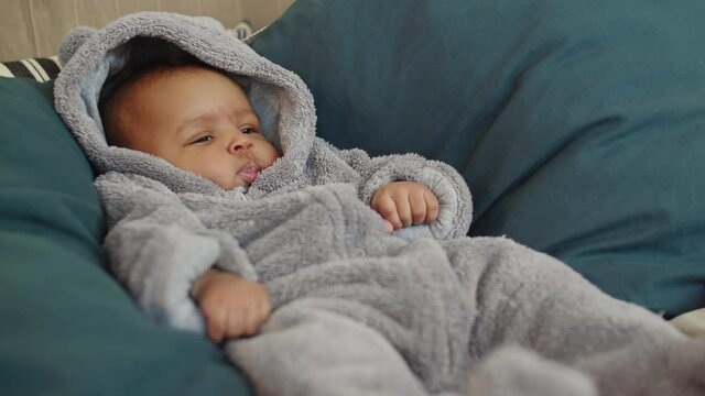 Close up of sweet mixed-race baby wearing warm rompers lying in bed at home