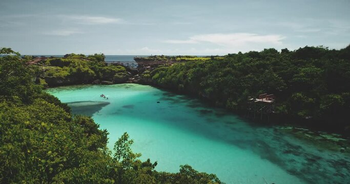 Turquoise lake with resting people aerial view. Tourists swimming at azure crystal clean lagoon admist green tropic trees landscape. Cinematic summer vacation at salt water Weekuri loch in drone shot