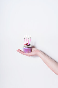 Female Hand holding a chocolate cupcake in front of white background