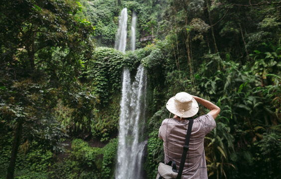 Mature man taking photograph of waterfall in Bali