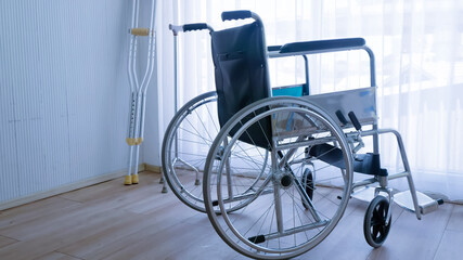 Empty modern wheelchair and walking stick or canes in hospital room.