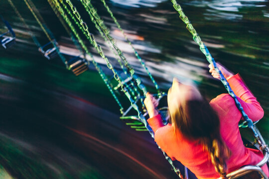 Young woman riding on a swing carousel in amusement park