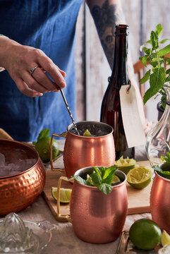 Woman mixing Moscow mule cocktails at a table.