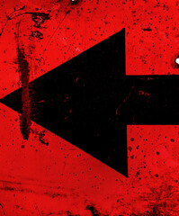 old and black metal arrow sign points to the left on a red background