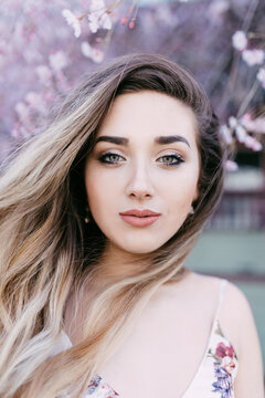 A young woman standing under a cherry blossom tree
