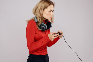Woman with headphones controller in hands a console game fun leisure red jacket lifestyle light...