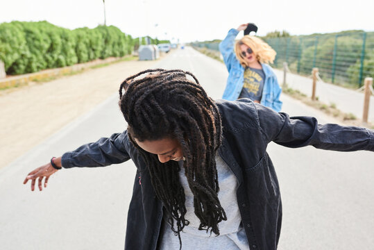 Girl with dreadlocks looking down with arms widened.