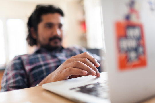 Young south asian man working on a laptop.