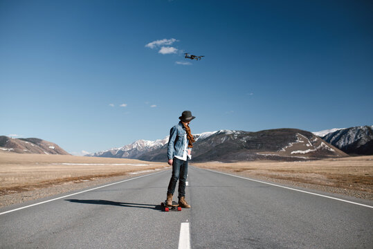 Male on skateboard looking at drone flying