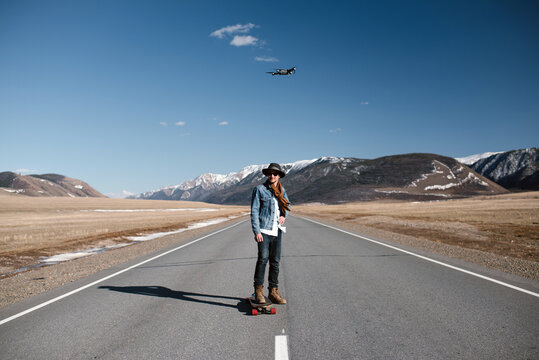 Male on skateboard looking at drone flying
