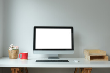 Minimal workspace with white screen computer and office supplies on white table.