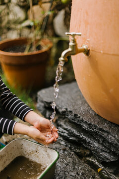 Hand in Water Spigot of Rain Barrel