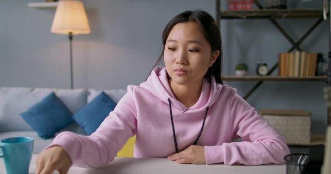 Young focused asian university student watching a video lecture with attention. Student studying at home, concentrating on a lesson 4k footage