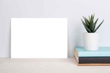 Blank mockup paper sheet copy space and plants in potted on book on wooden table, poster and invitation with empty on desk, card decoration your design or branding, simplicity and minimal, nobody.