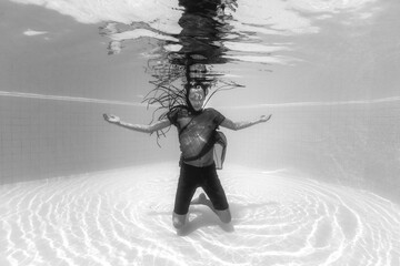 Beautiful man dressed in black floating in the pool