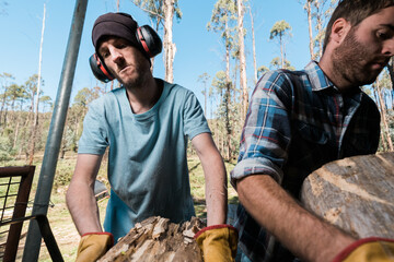 Men lifting timber ready for splitting