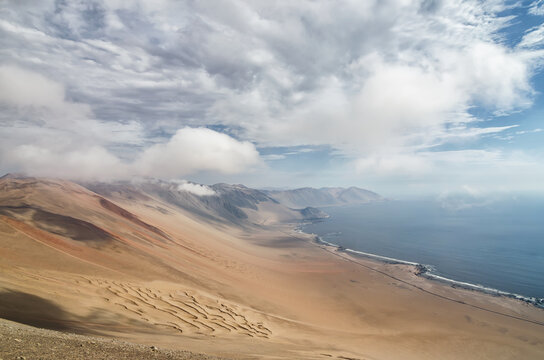 Stunning view to sand slope of desert meeting ocean and low clou