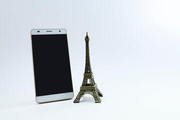A smartphone and Eiffel tower ornament on white background 