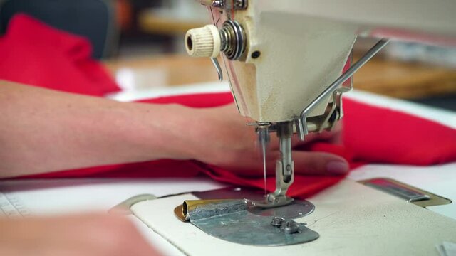 Closeup of female hands working on a sewing machine.