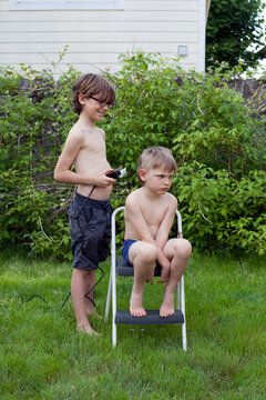 Older brother cuts younger brother's hair with clippers