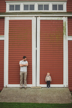 Dad and young son standing in front of red barn door of red barn
