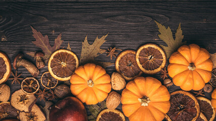 Autumn background with candied fruits, oranges, apples, nuts, anise, mushrooms, acorns and pumpkin. Dry tree leaves. Natural wooden background with copy space. 
