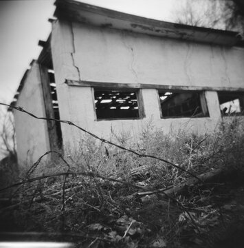 Deserted house showing barbed wire and overgrowth weeds