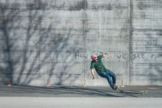 Teenager falls off his longboard in front of a wall