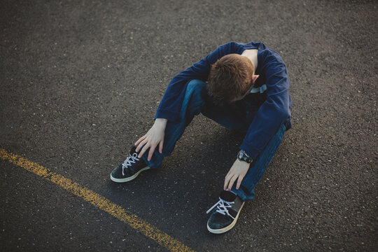 lonely sad middle school boy sitting alone on concrete