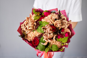 Red tones Beautiful bouquet of mixed flowers in womans hands. the work of the florist at a flower shop. Handsome fresh bouquet. Flowers delivery