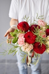 Red tones Beautiful bouquet of mixed flowers in womans hands. the work of the florist at a flower shop. Handsome fresh bouquet. Flowers delivery