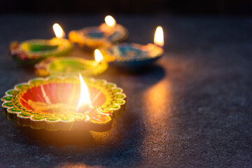 Close up of clay lit light a fire already on Diya or oil lamp, studio shot on concrete background, Decoration of Hinduism rangoli, Happy celebration Deepavali or Diwali festival concept