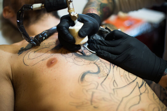Making Tattoo: a man continue his work in progress tattoo on his chest