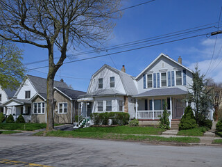 Residential street with modest detached houses with aluminum siding or clapboard