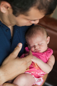 A first-time father cradles his infant daughter in his arms.