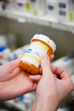 Pharmacy: Woman Putting Warning Label On Bottle