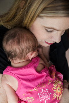 A first-time mother lovingly holds her mixed-race newborn baby girl.