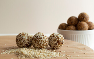 Homemade healthy vegan raw energy balls on wooden board. Made with dried dates, walnuts, almonds and cashews in sesame seeds, matcha powder and carob. The concept of healthy and vegetarian food. 