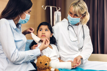 Woman doctor wearing protective mask for girl service help support discussing and consulting talk to little girl patient and check up information in hospital