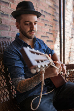 handsome brazillian man wearing fedora, playing guitar